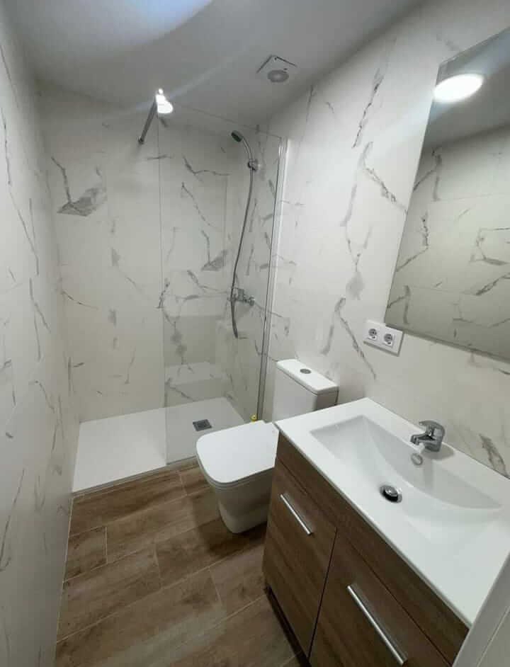 Baño moderno con placa decorativa imitación mármol en Reus.