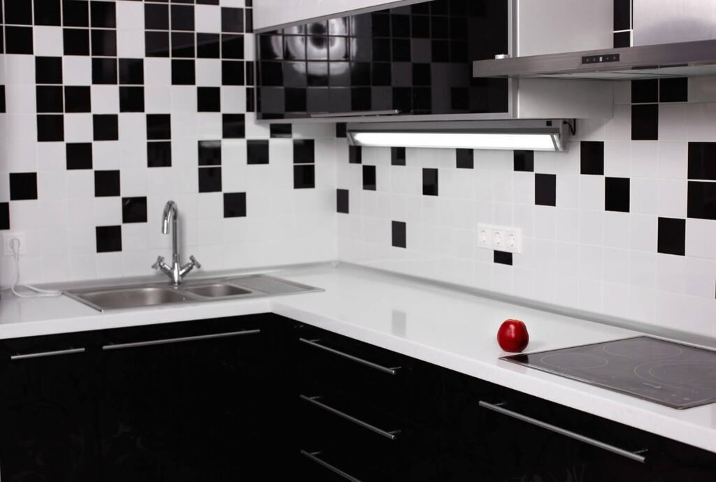 Diseño moderno de cocina en calle Misericòrdia, Reus Cocina reformada con azulejos en patrón geométrico blanco y negro y encimera negra en Reu