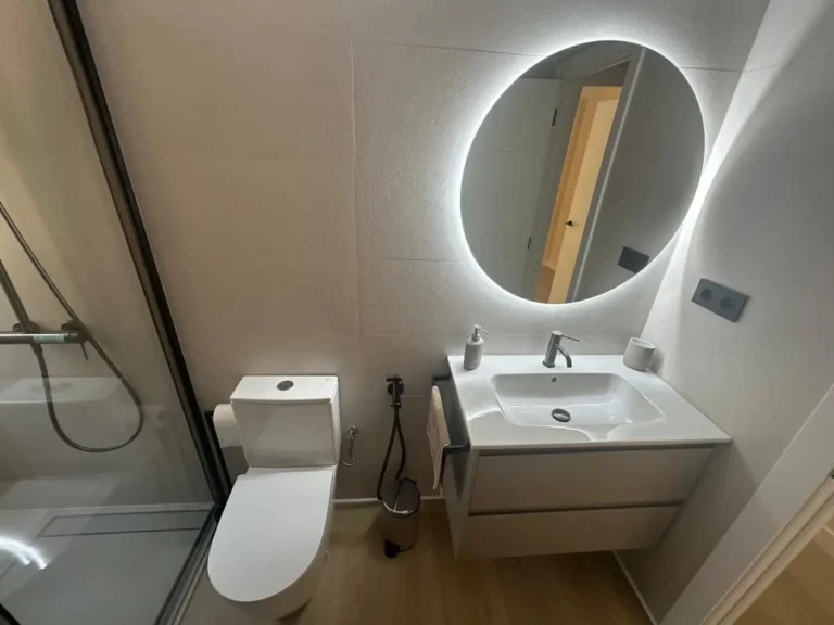 Baño con espejo LED de forma orgánica y mueble suspendido blanco – LUCMAR