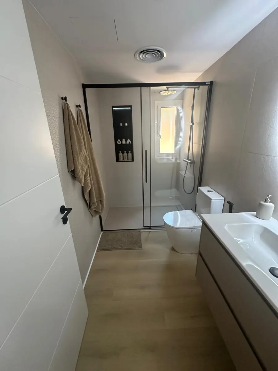Baño reformado con mampara de perfil negro, hornacina LED y suelo efecto madera – LUCMAR