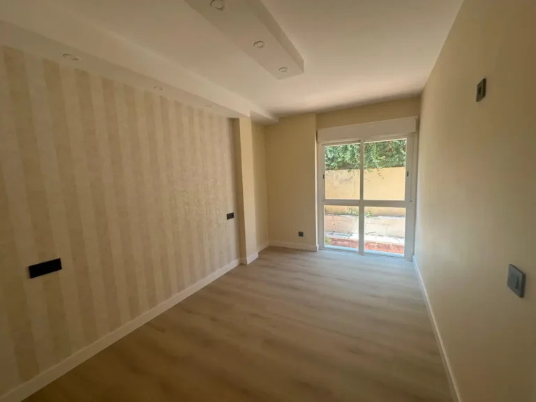 Dormitorio reformado con papel pintado de rayas, suelo laminado y salida al patio – LUCMAR